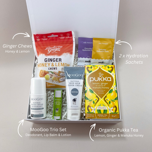 Chemotherapy care gift box laid out with MooGoo skin milk lotion, sensitive lip balm, Buderim ginger chews with honey and lemon, Pukka organic tea and Sodii hydration sachets. With labels.