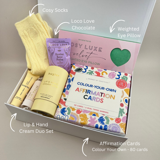 The Gentle Days Gift Box with luxe weighted pillow, Loco Love chocolate, Huxter hand and lip cream duo, cosy socks and colour-your-own affirmation cards. With Labels.