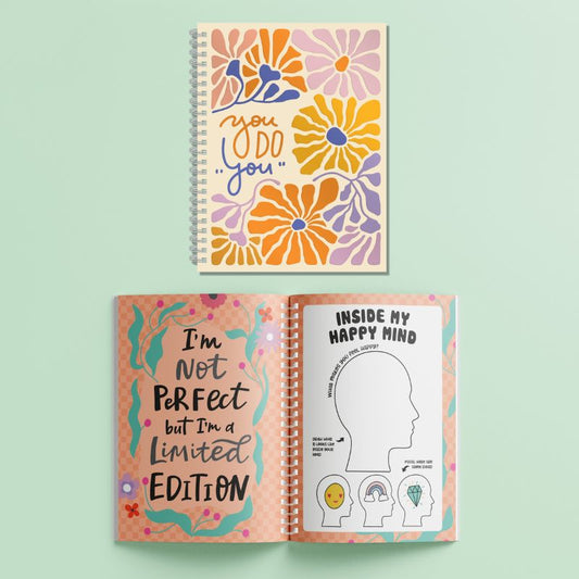 Colorful spiral-bound notebook with floral design and motivational text on a light green background