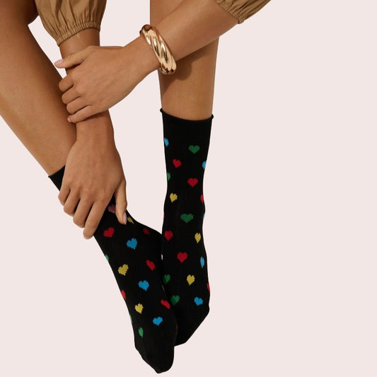 Black socks with colourful heart pattern worn by woman showing soft comfortable fabric and playful everyday design.