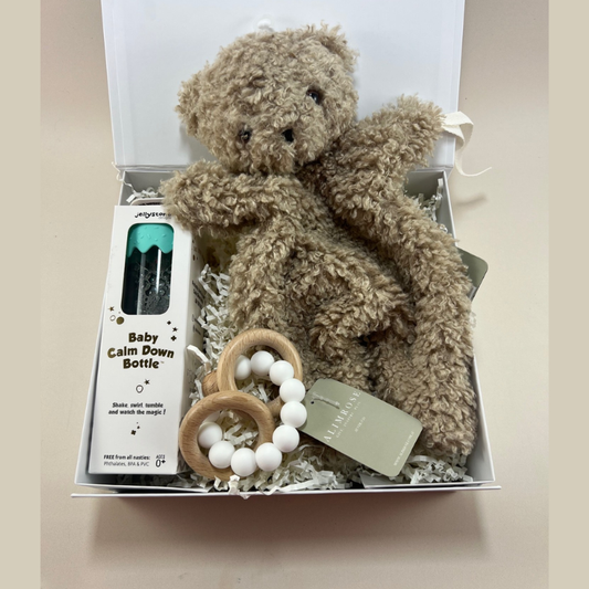 Baby gift box containing an Alimrose comforter, Alimrose wooden and silicone teether, and Jellystone Designs Baby Calm Down Bottle.