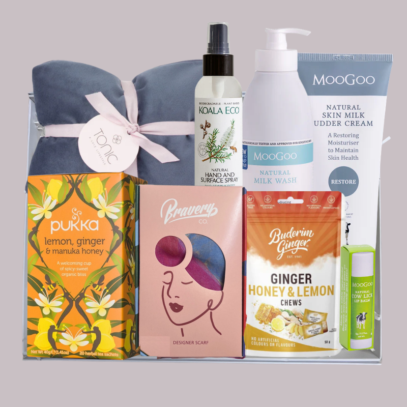 Luxury cancer and chemo care gift box with silk scarf, heat pillow, MooGoo skincare, tea and ginger chews arranged in a white rigid gift box.