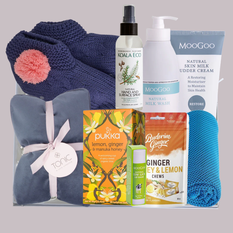 Cancer and chemo comfort gift box with heat pillow, slippers, ice towel, MooGoo skincare, tea and ginger chews arranged in a premium white gift box.
