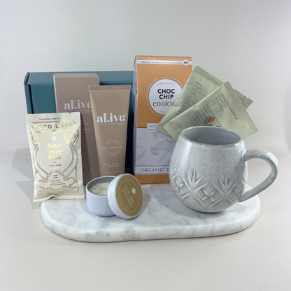 Carer gift box with speckled ceramic mug, Love Tea sachets, choc chip cookies, Al.ive Body hand cream, Loco Love chocolate and “You Are Amazing” candle