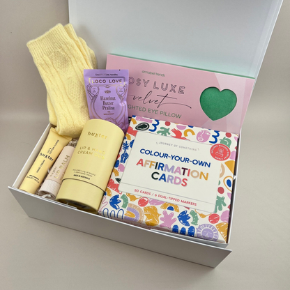 The Gentle Days Gift Box with luxe weighted pillow, Loco Love chocolate, Huxter hand and lip cream duo, cosy socks and colour-your-own affirmation cards