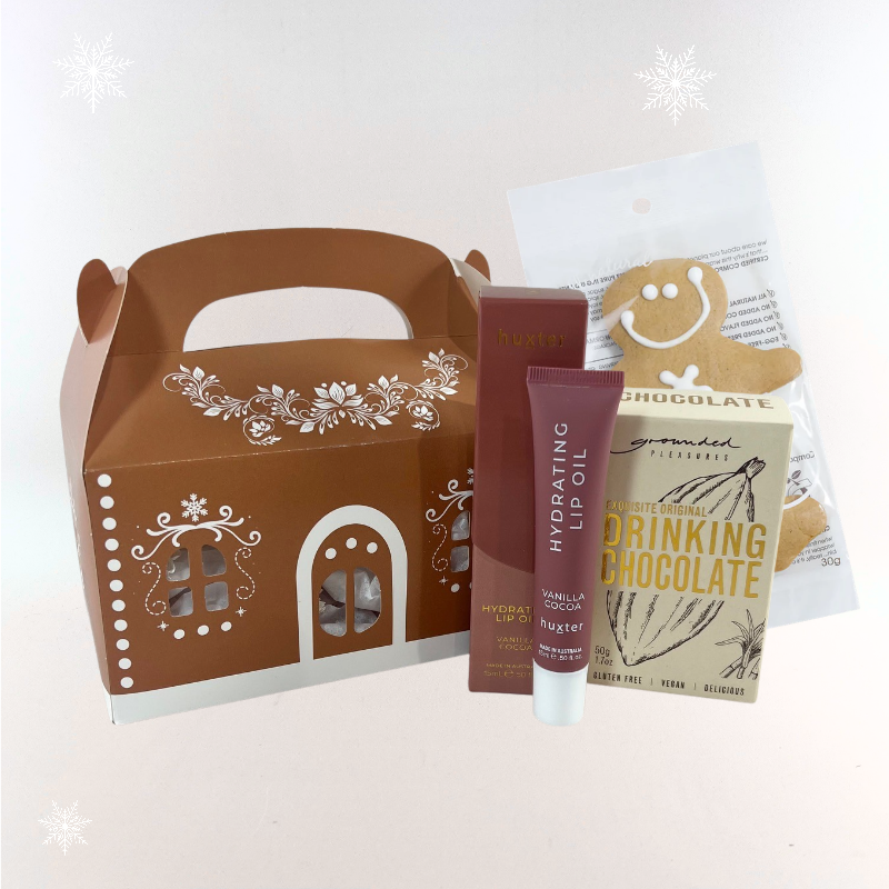 Gingerbread house Christmas gift box with Huxter Vanilla Cocoa lip oil, Grounded Pleasures drinking chocolate and gingerbread man