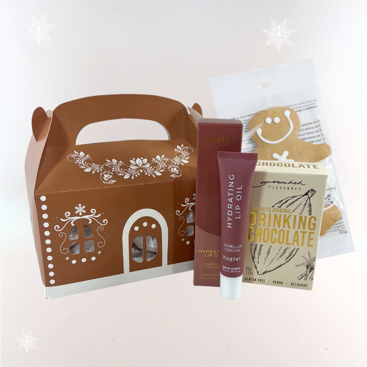 Gingerbread house Christmas gift box with Huxter Vanilla Cocoa lip oil, Grounded Pleasures drinking chocolate and gingerbread man