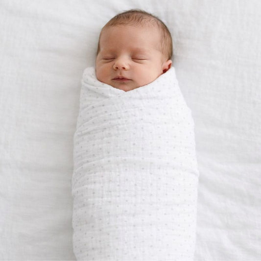 Newborn baby wrapped in grey spot muslin swaddle blanket