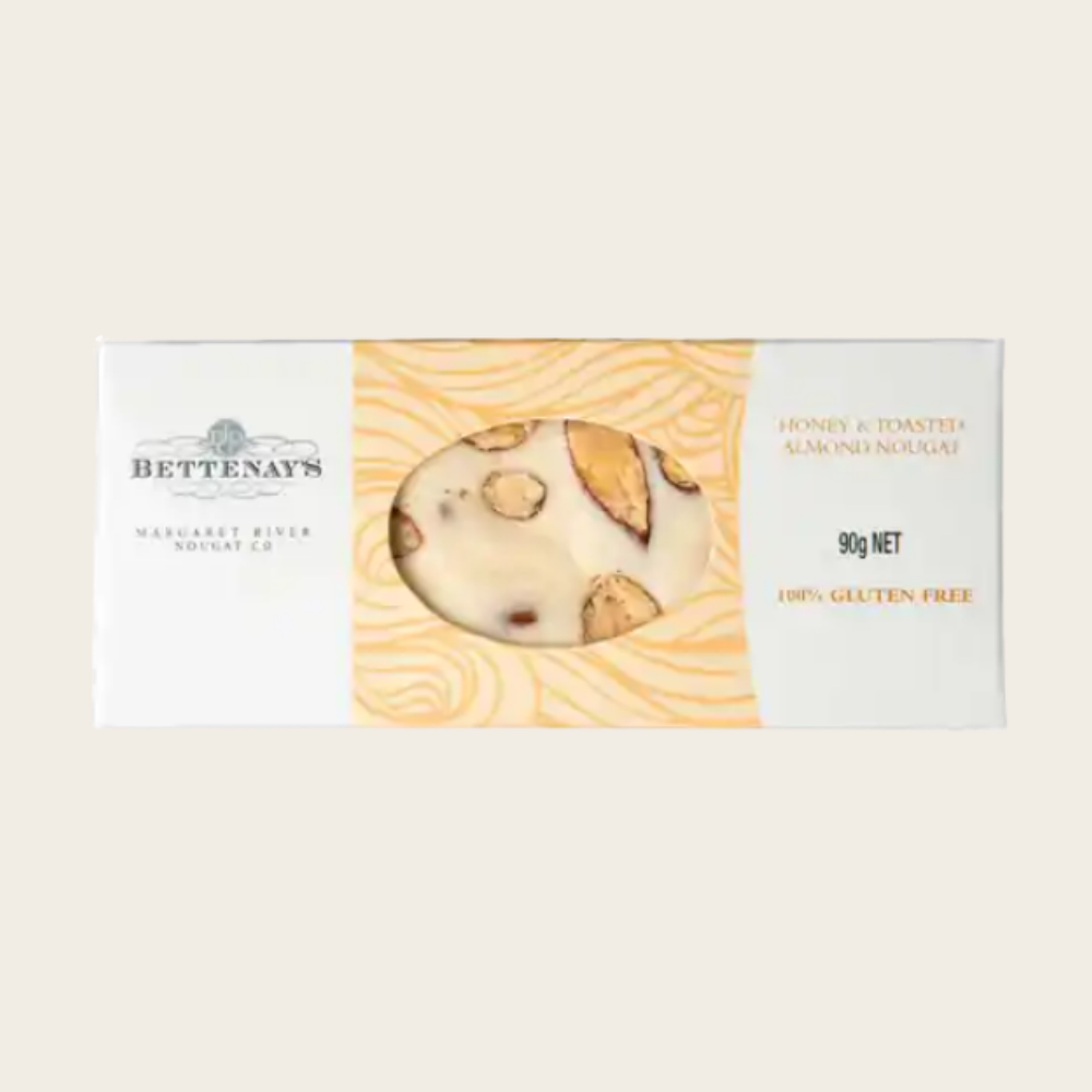 Bettenay's honey and toasted almond nougat 90g in a white and gold box with a window showing the white nougat studded with toasted almonds