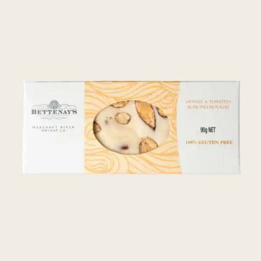 Bettenay's honey and toasted almond nougat 90g in a white and gold box with a window showing the white nougat studded with toasted almonds