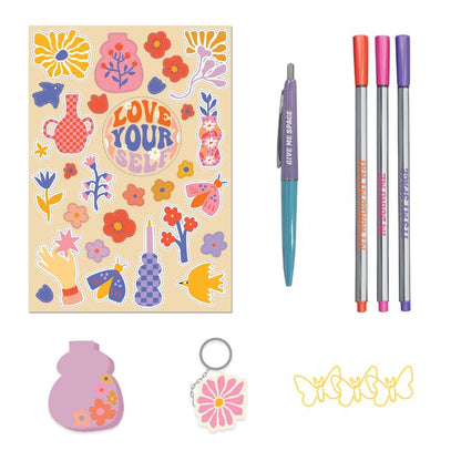 Stationery items including a notebook with stickers, pens, a keychain, and paper clips on a white background.