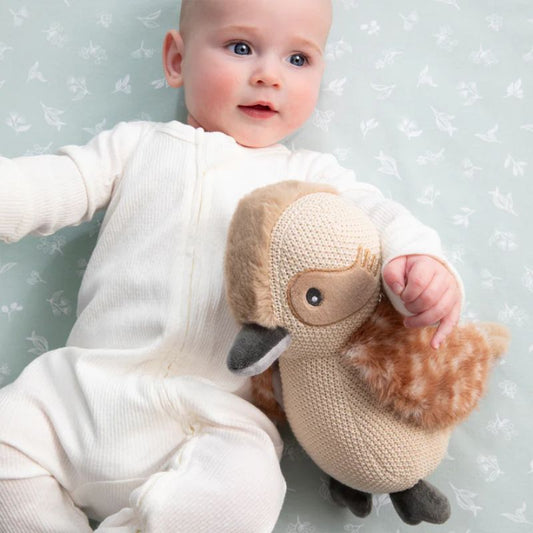 Baby lying on blanket holding Kenny the Kookaburra Australian plush toy