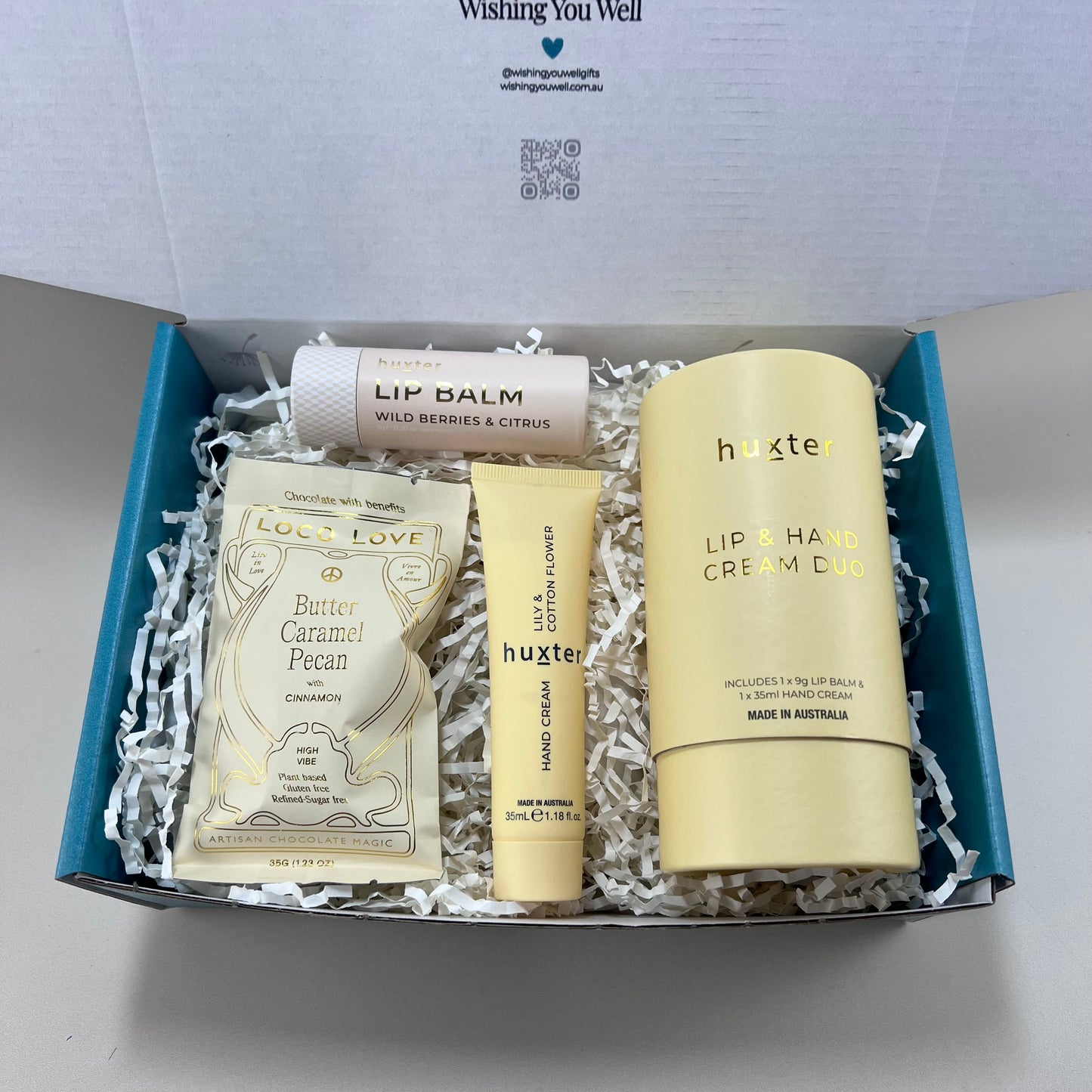 Huxter hand cream and lip balm duo alongside a Loco Love artisan chocolate bar, neatly arranged in a recyclable gift box.