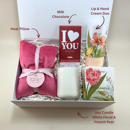 Close up of Mothers Day gift box contents showing GNAW I Love You milk chocolate bar, Huxter limited edition lip and hand cream duo and Huxter white florals and french pear soy candle labels