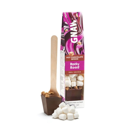 Gnaw Rocky Road hot chocolate spoon with marshmallows and chocolate block on wooden spoon next to colourful packaging.